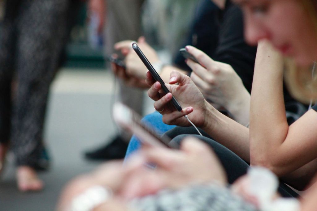 young adults staring at mobile devices society enthralled with spectacle